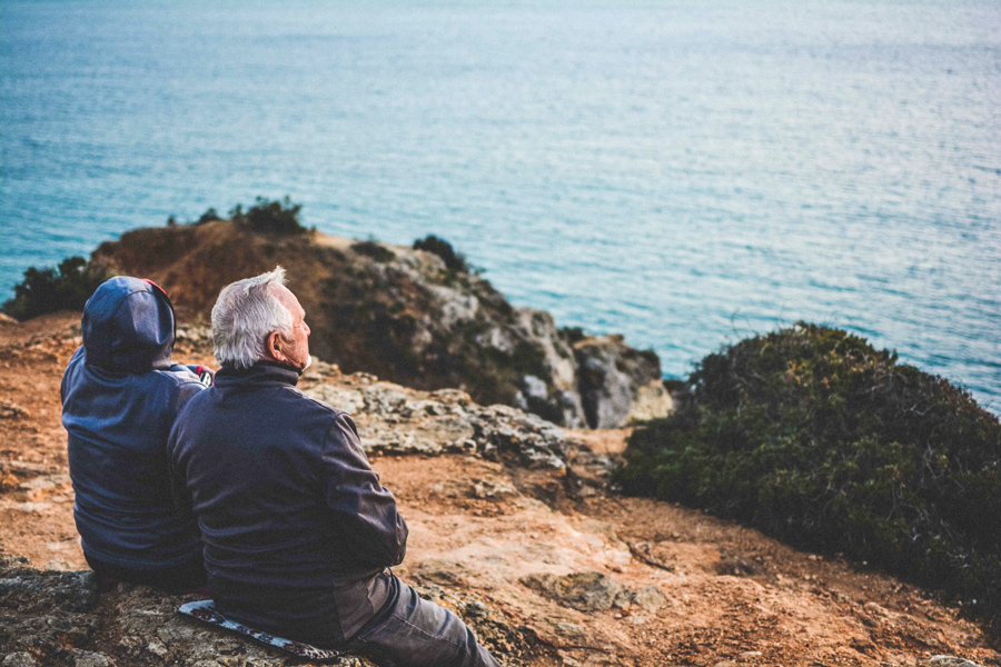 older couple sitting on the rocky shore